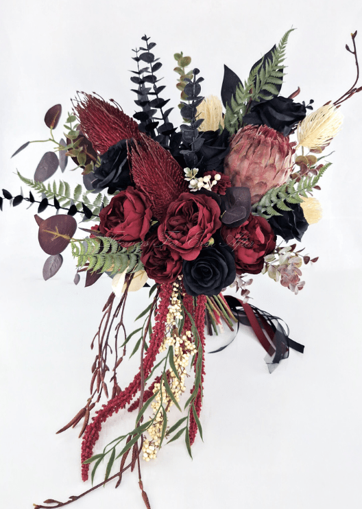 Artificial wedding cascading bridal bouquet with burgundy and black faux roses, pink protea, burgundy spiky blooms and trailing foliage. Made in Melbourne by Flowers For Ever After, shipping Australia and Worldwide.