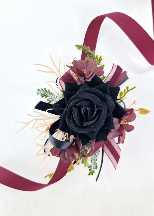Artificial wedding wrist corsage with a black faux rose, burgundy flowers, fine pale sprigs and black and burgundy ribbons. For formals, proms and ball occasions. Made in Melbourne by Flowers For Ever After, shipping Australia and Worldwide.