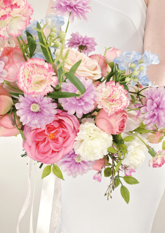Artificial wedding bouquet close-up with pink faux roses, lilac daisies, pink-edged carnations, white flowers and pale blue sprigs. Made in Melbourne by Flowers For Ever After, shipping Australia and Worldwide.