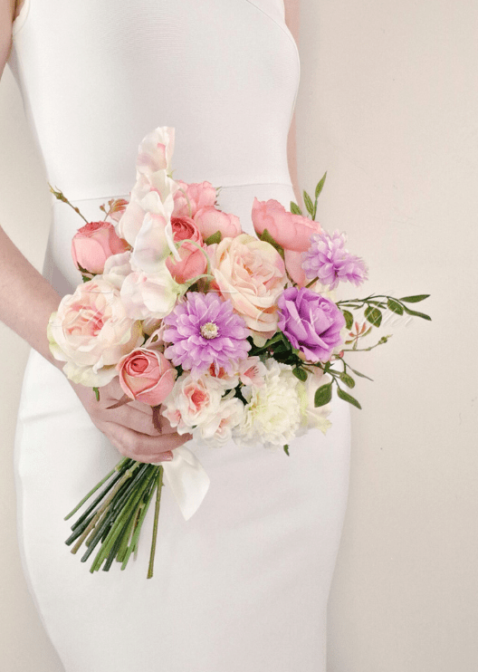 Artificial wedding bridesmaid bouquet, angled view of pink and purple faux roses, lilac daisies, white flowers and green leaves. Made in Melbourne by Flowers For Ever After, shipping Australia and Worldwide.