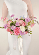 Artificial wedding bridal bouquet held by a bride, with pink faux roses, lilac daisies, white flowers, pale blue sprigs and ivory ribbons. Made in Melbourne by Flowers For Ever After, shipping Australia and Worldwide.