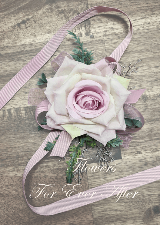 Artificial wedding wrist corsage with a pale lavender faux rose, small white flowers, green leaves and long ivory ribbons. For formals, proms and ball occasions. Made in Melbourne by Flowers For Ever After, shipping Australia and Worldwide.