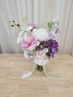 A mixed artificial floral bridesmaid bouquet with purple and white flowers, including lilac roses, purple hydrangea, lilac sweet pea, and orchids.  Made in Melbourne Australia, by Australia's best silk bridal florist