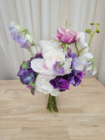 A mixed artificial floral bridesmaid bouquet with purple and white flowers, including lilac roses, purple hydrangea, lilac sweet pea, and orchids.  Made in Melbourne Australia, by Australia's best silk bridal florist
