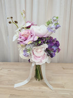 A mixed artificial floral bridesmaid bouquet with purple and white flowers, including lilac roses, purple hydrangea, lilac sweet pea, and orchids.  Made in Melbourne Australia, by Australia's best silk bridal florist