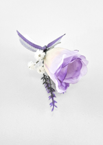 Artificial wedding boutonniere, overhead view of a lilac faux rosebud, tiny white flowers, purple sprigs and purple ribbon. For formals, proms and ball occasions. Made in Melbourne by Flowers For Ever After, shipping Australia and Worldwide.
