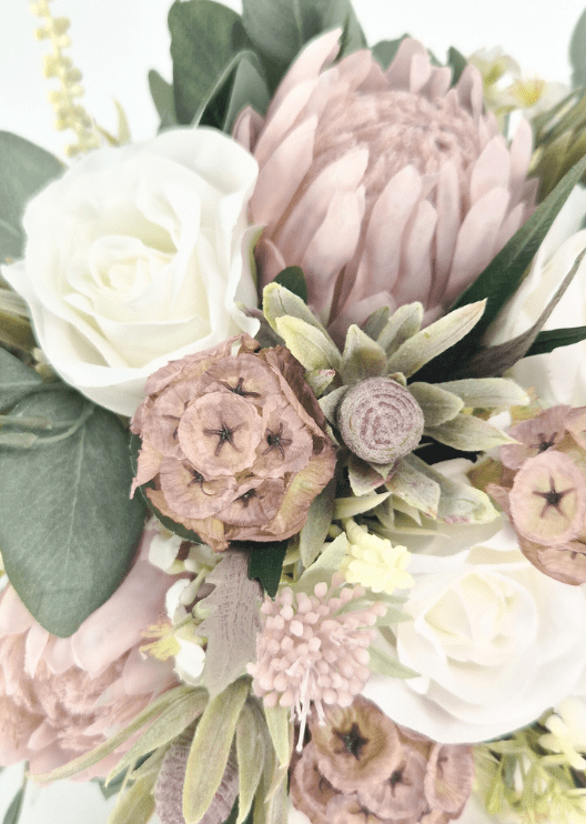Artificial wedding bouquet detail showing blush pink faux protea, ivory roses, tan lotus pods, grey seedpod and pale pink pompom bloom. Made in Melbourne by Flowers For Ever After, shipping Australia and Worldwide.