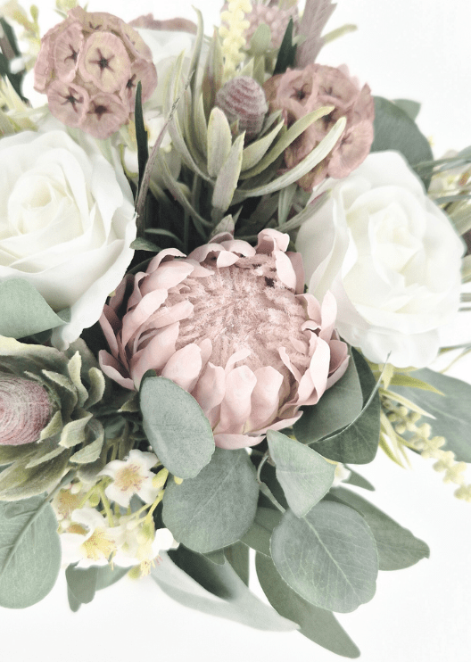 Artificial wedding bouquet close-up with blush pink faux protea, ivory roses, tan lotus pods, cream flower sprigs and eucalyptus. Made in Melbourne by Flowers For Ever After, shipping Australia and Worldwide.