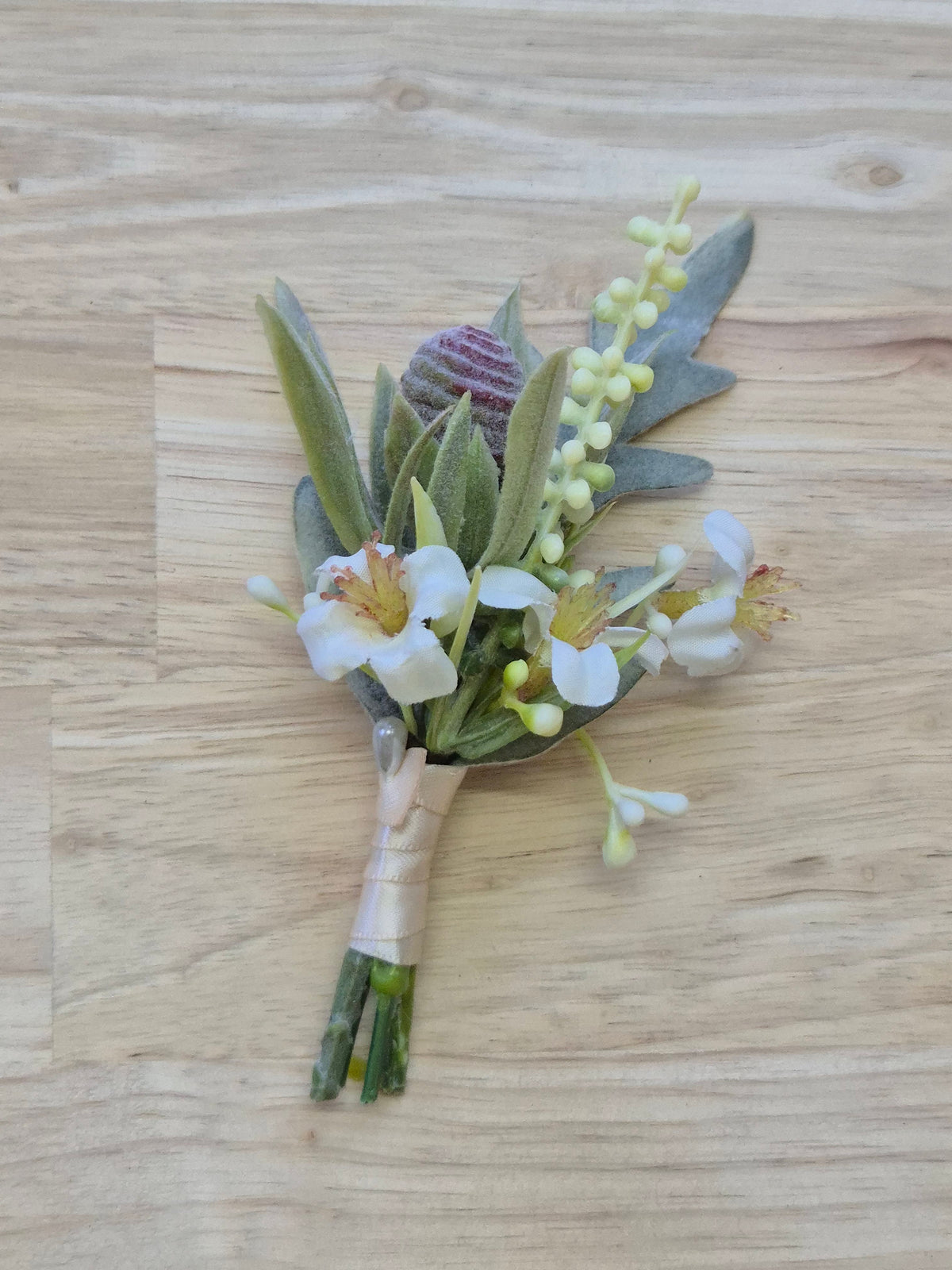 Artificial wedding boutonniere with protea bud, pale budding sprigs and muted green leaves. For formals, proms and ball occasions. Made in Melbourne by Flowers For Ever After, shipping Australia and Worldwide.