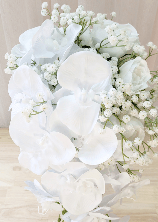 Artificial wedding bridal bouquet, angled view of white faux orchids, roses and green leaves. Made in Melbourne by Flowers For Ever After, shipping Australia and Worldwide.