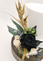 Artificial wedding cake decoration close-up with a black faux rose, cream blooms, green berries and golden sprigs. For birthday, event and celebration cakes. Made in Melbourne by Flowers For Ever After, shipping Australia and Worldwide.