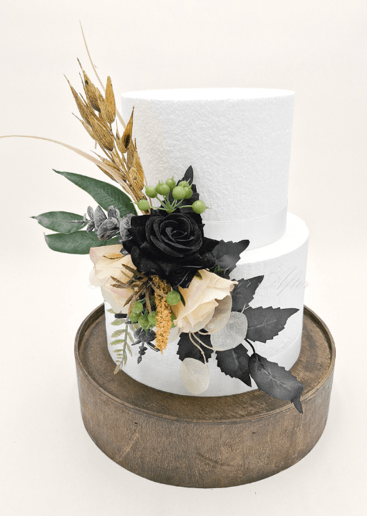 Artificial wedding cake decoration with a black faux rose, cream blooms, green berries, golden sprigs and dark foliage. For birthday, event and celebration cakes. Made in Melbourne by Flowers For Ever After, shipping Australia and Worldwide.