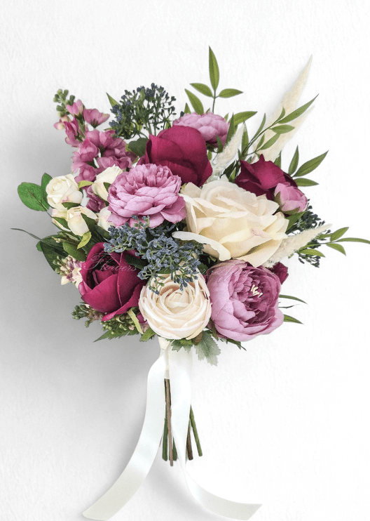 Artificial wedding bouquet with burgundy and ivory faux roses, mauve ranunculus and peonies, blue-grey berries, pink flower spikes and pale plumes. Made in Melbourne by Flowers For Ever After, shipping Australia and Worldwide.