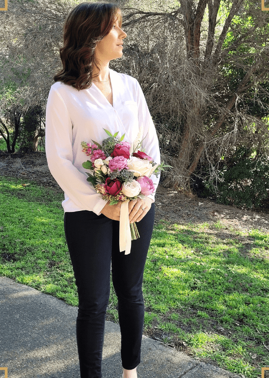 Artificial wedding bouquet held by a person, with burgundy and ivory faux roses, mauve blooms, green foliage and ivory ribbon tails. Made in Melbourne by Flowers For Ever After, shipping Australia and Worldwide.