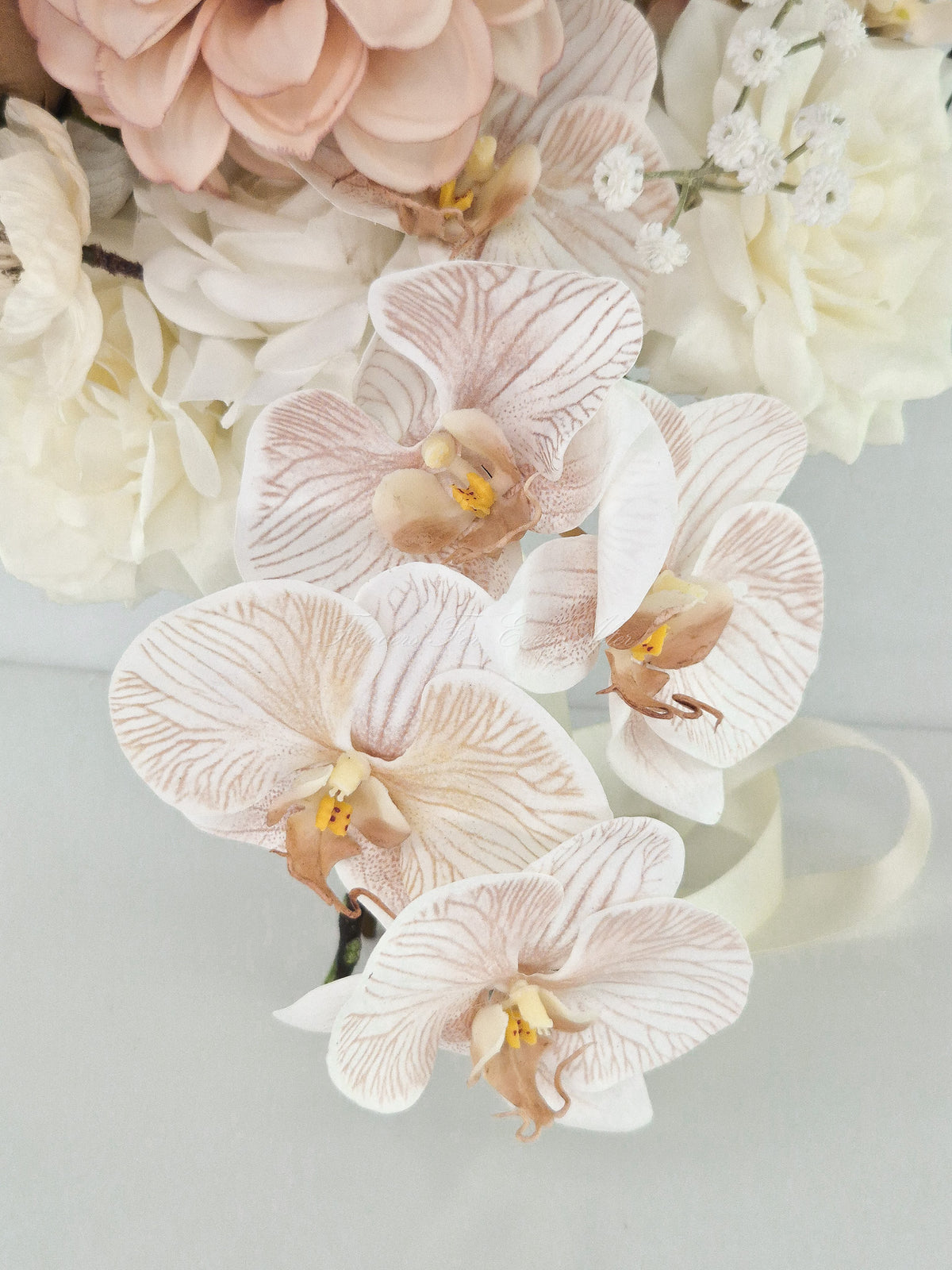 Faux bridal bouquet featuring latte phalaenopsis orchids, dusty blush dahlias, and ivory roses with cream satin ribbon.