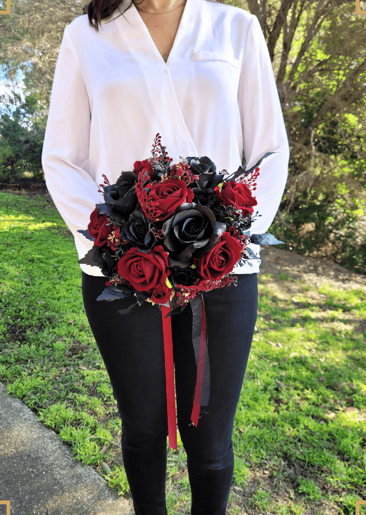 Artificial wedding bridal bouquet held by a bride, with mixed faux flowers, green leaves and trailing ribbon. Made in Melbourne by Flowers For Ever After, shipping Australia and Worldwide.