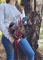 Artificial wedding bouquet close-up held at waist height, showing black and burgundy faux calla lilies and roses with bronze sprigs and long ribbons. Made in Melbourne by Flowers For Ever After, shipping Australia and Worldwide.