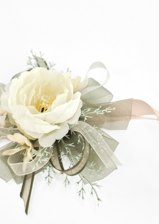 Artificial wedding wrist corsage, side view of an ivory faux rose, cream flowers, olive ribbon loops and blush ribbon tail. For formals, proms and ball occasions. Made in Melbourne by Flowers For Ever After, shipping Australia and Worldwide.