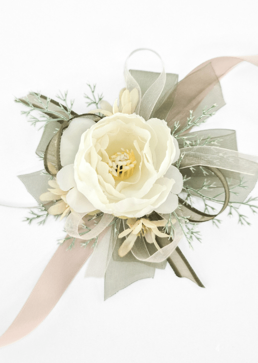 Artificial wedding wrist corsage with an ivory faux rose, cream star-shaped flowers, fine pale sprigs, olive and ivory ribbon loops and blush ribbon tails. For formals, proms and ball occasions. Made in Melbourne by Flowers For Ever After, shipping Australia and Worldwide.