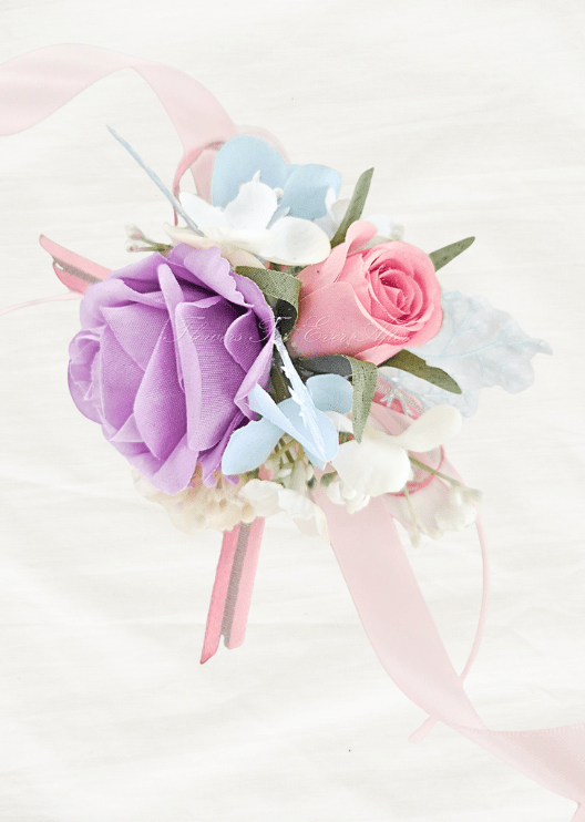Artificial wedding wrist corsage close-up with lilac and pink faux roses, pale blue flowers, white filler blooms and pink ribbons. For formals, proms and ball occasions. Made in Melbourne by Flowers For Ever After, shipping Australia and Worldwide.