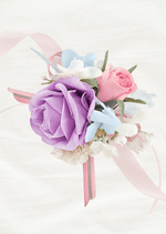 Artificial wedding wrist corsage with lilac and pink faux roses, pale blue and white flowers and pink ribbon tails. For formals, proms and ball occasions. Made in Melbourne by Flowers For Ever After, shipping Australia and Worldwide.