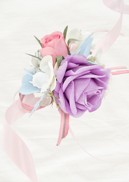 Artificial wedding wrist corsage, angled view of a lilac faux rose, pink rosebud, pale blue and white flowers and pink ribbons. For formals, proms and ball occasions. Made in Melbourne by Flowers For Ever After, shipping Australia and Worldwide.