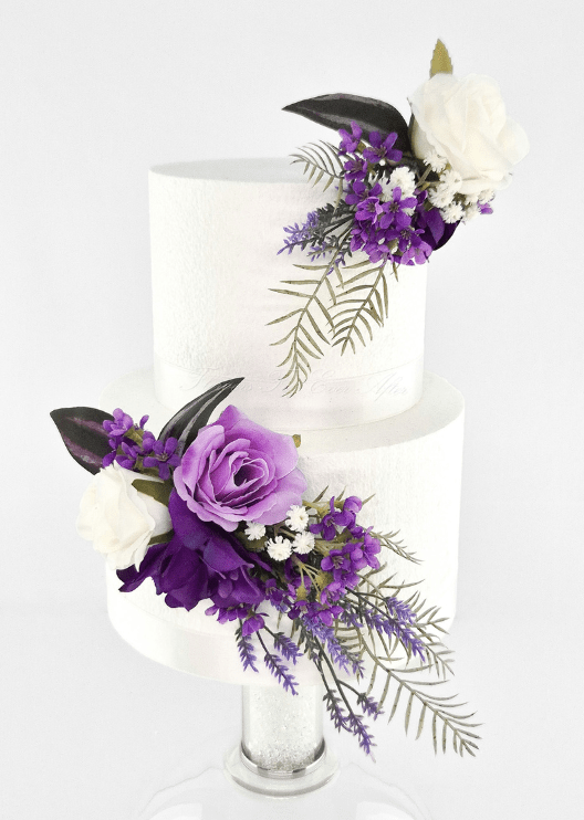 Artificial wedding cake decoration, angled view of purple and white faux roses, small purple flowers and trailing fern-like foliage. For birthday, event and celebration cakes. Made in Melbourne by Flowers For Ever After, shipping Australia and Worldwide.