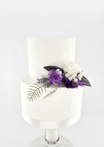 Artificial wedding cake decoration with a white faux rose, purple blossoms, tiny white flowers and fern-like leaves at the tier join. For birthday, event and celebration cakes. Made in Melbourne by Flowers For Ever After, shipping Australia and Worldwide.