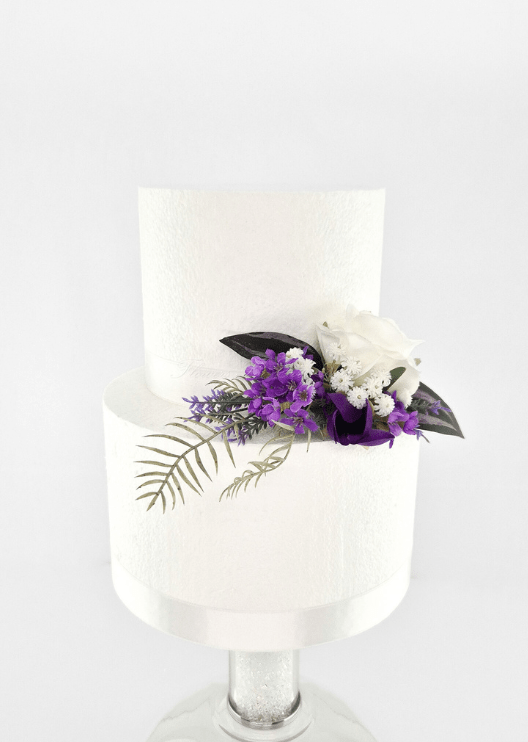 Artificial wedding cake decoration with a white faux rose, purple blossoms, tiny white flowers and fern-like leaves at the tier join. For birthday, event and celebration cakes. Made in Melbourne by Flowers For Ever After, shipping Australia and Worldwide.