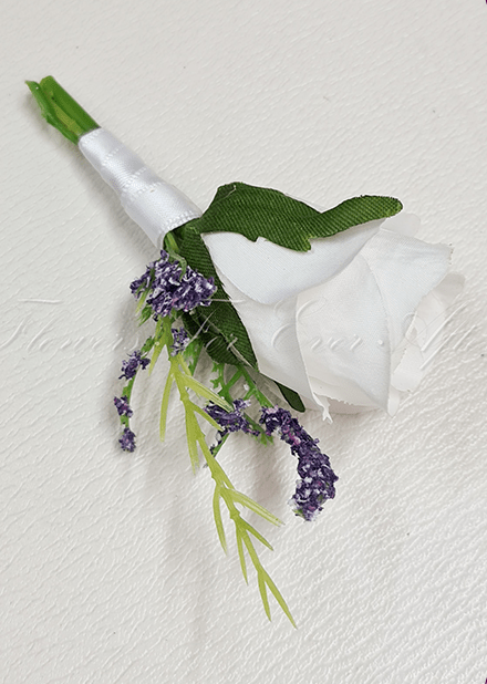 Artificial wedding boutonniere, angled view of a white faux rose, pale sprigs and green foliage. For formals, proms and ball occasions. Made in Melbourne by Flowers For Ever After, shipping Australia and Worldwide.