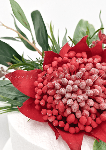 Artificial wedding cake decoration close-up showing red faux waratah petals, yellow sprigs and green leaves. For birthday, event and celebration cakes. Made in Melbourne by Flowers For Ever After, shipping Australia and Worldwide.