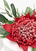 Artificial wedding cake decoration close-up showing red faux waratah petals, yellow sprigs and green leaves. For birthday, event and celebration cakes. Made in Melbourne by Flowers For Ever After, shipping Australia and Worldwide.