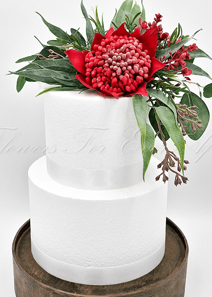 Artificial wedding cake decoration, angled view of red faux waratah flowers, yellow wattle and green foliage. For birthday, event and celebration cakes. Made in Melbourne by Flowers For Ever After, shipping Australia and Worldwide.