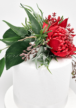 Artificial wedding cake decoration close-up with red faux waratah, yellow wattle sprigs and green leaves. For birthday, event and celebration cakes. Made in Melbourne by Flowers For Ever After, shipping Australia and Worldwide.
