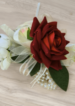 Artificial wedding wrist corsage, angled view of red and cream faux roses, ivory ribbon loops and pearl-style bracelet. For formals, proms and ball occasions. Made in Melbourne by Flowers For Ever After, shipping Australia and Worldwide.