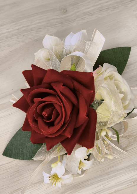 Artificial wedding wrist corsage with red and cream faux roses, tiny white flowers, broad green leaves and ivory ribbons. For formals, proms and ball occasions. Made in Melbourne by Flowers For Ever After, shipping Australia and Worldwide.