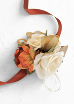 Artificial wedding wrist corsage with rust-orange and cream faux roses, gold ribbon loops and long rust-coloured ribbon ties. For formals, proms and ball occasions. Made in Melbourne by Flowers For Ever After, shipping Australia and Worldwide.