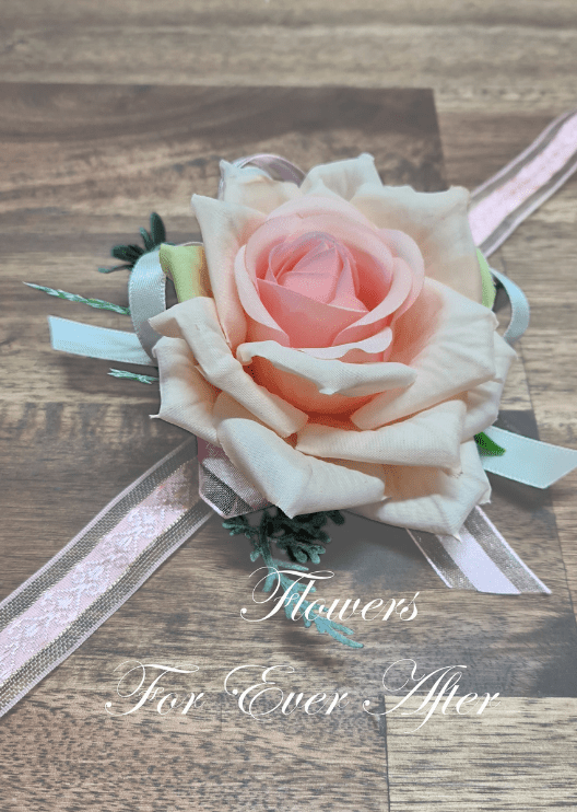 Artificial wedding wrist corsage with a salmon pink faux rose, pale filler flowers, green leaves and ivory ribbons. For formals, proms and ball occasions. Made in Melbourne by Flowers For Ever After, shipping Australia and Worldwide.