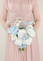 Artificial wedding bridesmaid bouquet held in both hands, with white faux roses, pale blue flowers and small white sprigs. Made in Melbourne by Flowers For Ever After, shipping Australia and Worldwide.