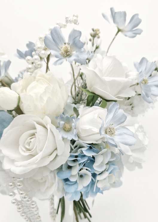 Artificial wedding bouquet close-up with white faux roses, pale blue flowers, blue hydrangea and dangling pearl strands. Made in Melbourne by Flowers For Ever After, shipping Australia and Worldwide.