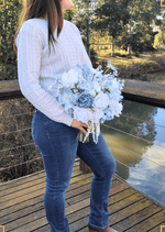 Artificial wedding bridal bouquet held in both hands, with white and dusty blue faux roses, pale blue flowers and pearl strands. Made in Melbourne by Flowers For Ever After, shipping Australia and Worldwide.