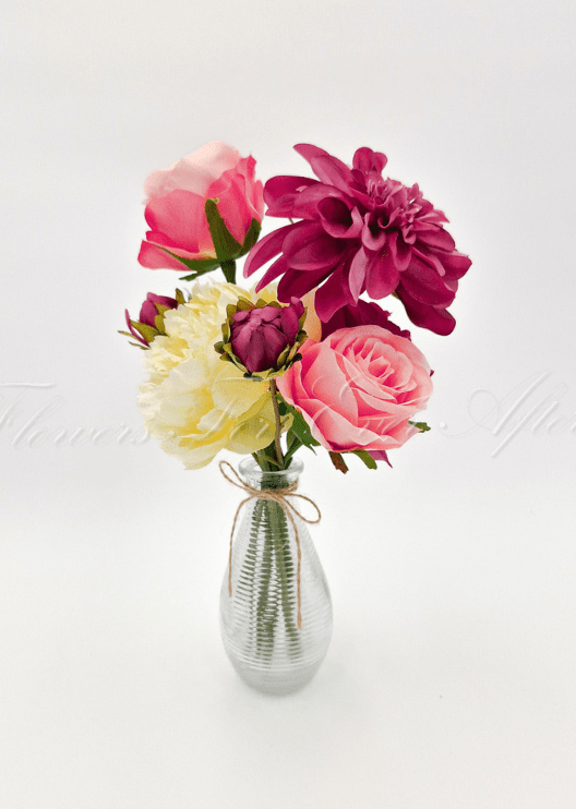 Artificial wedding table arrangement with pink and burgundy faux roses, a burgundy dahlia and cream blooms in a twine-tied glass bottle. Made in Melbourne by Flowers For Ever After, shipping Australia and Worldwide.