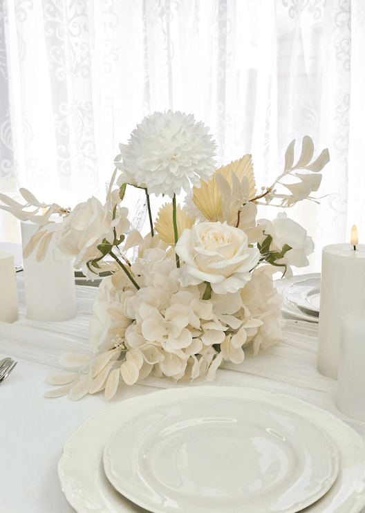Artificial wedding table centrepiece with clustered white faux flowers and green foliage in a low arrangement. Made in Melbourne by Flowers For Ever After, shipping Australia and Worldwide.