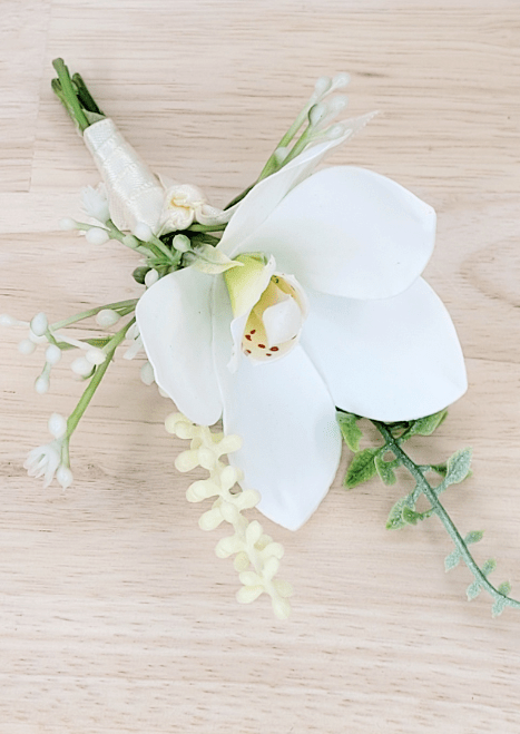 Artificial wedding boutonniere, overhead view of white faux orchid, pale berry sprigs and fine green leaves. For formals, proms and ball occasions. Made in Melbourne by Flowers For Ever After, shipping Australia and Worldwide.