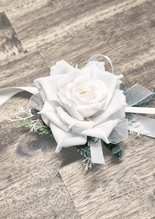 Artificial wedding wrist corsage, angled view of a white faux rose, silver sprigs and trailing ivory ribbons. For formals, proms and ball occasions. Made in Melbourne by Flowers For Ever After, shipping Australia and Worldwide.