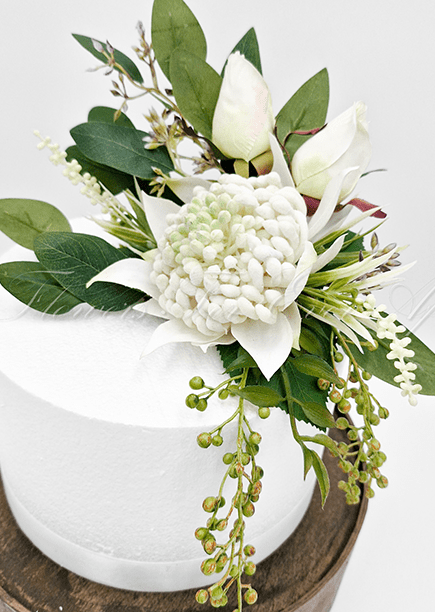 Artificial wedding cake decoration, angled view of white faux waratah blooms and green leaves. For birthday, event and celebration cakes. Made in Melbourne by Flowers For Ever After, shipping Australia and Worldwide.