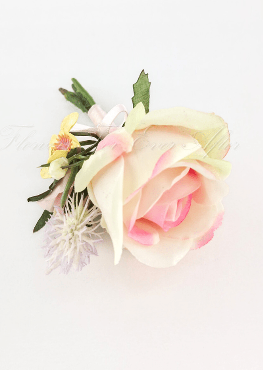 Artificial wedding boutonniere, top view of a cream-and-pink faux rose, tiny yellow flowers and pale sprigs. For formals, proms and ball occasions. Made in Melbourne by Flowers For Ever After, shipping Australia and Worldwide.
