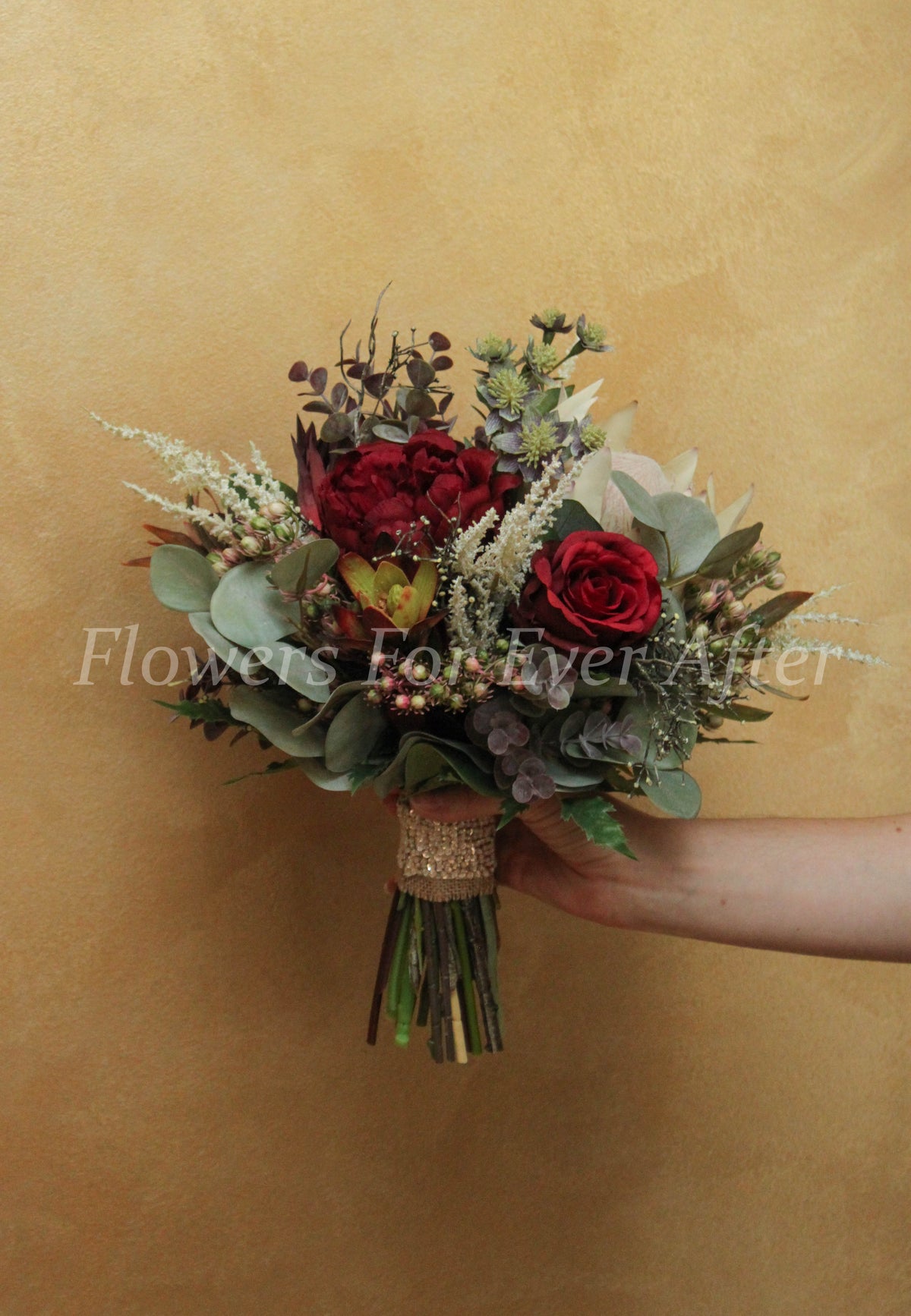 A rustic faux bridal bouquet in burgundy, green and white with australian natives and roses. Flowers by Flowers For Ever After