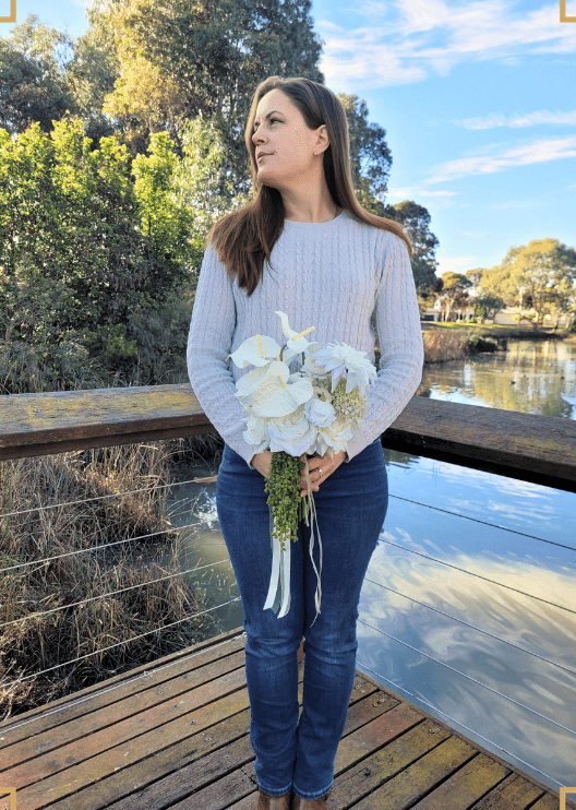 Artificial wedding bouquet held by a person, with white faux anthuriums and blooms, trailing green berries and long ribbons. Made in Melbourne by Flowers For Ever After, shipping Australia and Worldwide.
