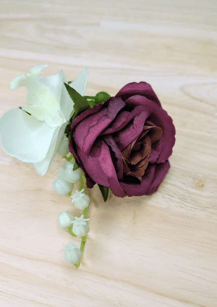 Artificial wedding boutonniere close-up with plum faux rose, white orchid and pale berry sprigs. For formals, proms and ball occasions. Made in Melbourne by Flowers For Ever After, shipping Australia and Worldwide.